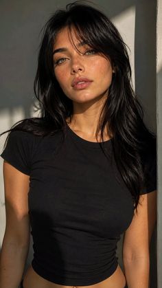 Woman with long black hair and freckles in a black t-shirt with soft lighting