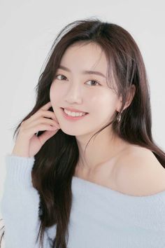 Smiling woman with long hair wearing a light blue off-shoulder sweater