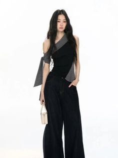 Woman with long black hair wearing an off-shoulder top and wide-leg jeans