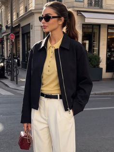 Woman in a black jacket and white pants on a city street