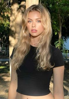 Blonde woman with blue eyes in a black t-shirt outdoors during golden hour