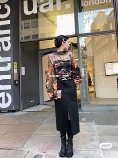 Woman in a long sleeve top and black skirt with split toe boots on a street