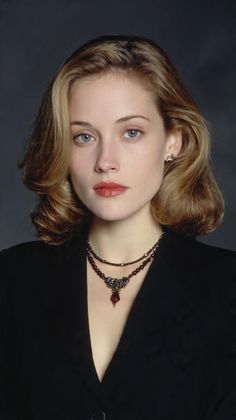 Woman with blonde hair and red lipstick wearing a black blazer and necklace
