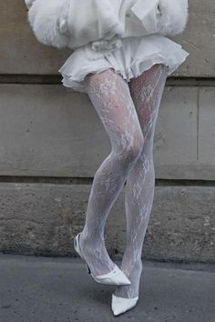 Person wearing white lace tights, a white skirt, and white heels outdoors