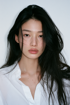 Woman with long black hair and freckles wearing a white shirt