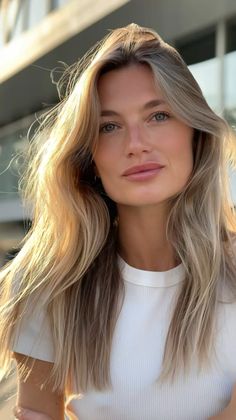 Woman with long blonde hair in a white shirt outdoors at golden hour
