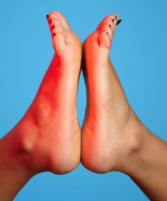 Two feet with black nail polish against a blue background with red lighting