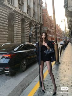 Woman in a black dress and blazer standing on a city street