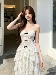 Woman in a white lace dress with black bows posing outdoors in daylight