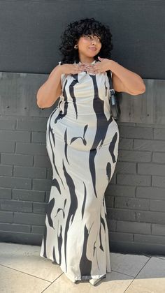 Woman with curly black hair wearing a black and white maxi dress outdoors