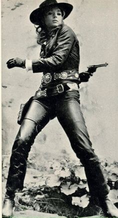Woman in a cowboy hat and leather outfit with a revolver in a holster