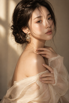Woman with braided hair and off-shoulder top in soft, warm lighting