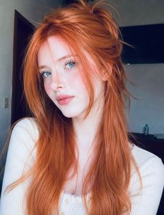 Woman with long red hair and blue eyes in a soft-lit indoor portrait