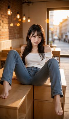 Woman in an off-shoulder top and jeans sitting on a counter in a cafe