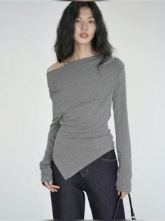 Woman with long dark hair wearing an off-shoulder top and dark jeans