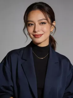 Woman in a navy blazer and black turtleneck with a gold necklace