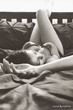 Woman in lingerie lying on a bed with legs raised, in black and white