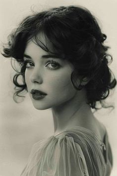 Woman with dark curly hair and red lipstick wearing sheer fabric, monochrome portrait