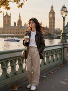 Woman in a brown leather jacket and wide leg pants by a river at golden hour