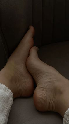 Bare feet crossed over each other on a dark surface