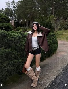 Woman in a brown jacket, short shorts, and tall boots outdoors