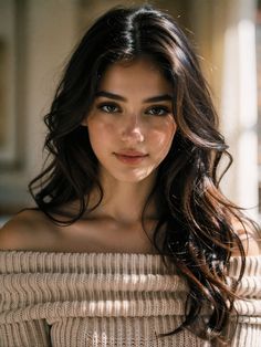 Woman with long dark hair wearing an off-shoulder sweater with soft lighting