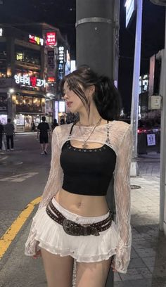 Woman in a crop top and mini skirt on a city street at night