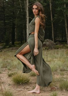 Woman in an olive green outfit with a high slit in a forest setting