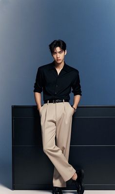 Man in a black shirt and khaki pants posing in a studio