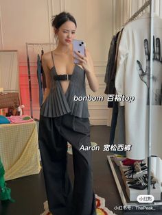 Woman in a pleated top and wide leg pants taking a mirror selfie