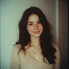 Young woman with long dark hair and freckles wearing a light sweater