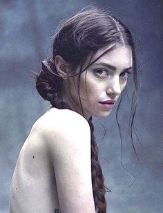 Woman with braided hair looking over her shoulder with exposed skin
