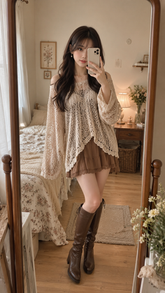 Woman in a crochet top and brown skirt taking a mirror selfie in a bedroom