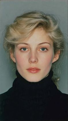 Woman with blonde hair and blue eyes wearing a black turtleneck