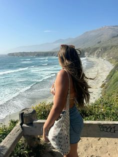 Woman with long hair looking out at the ocean from a cliffside viewpoint