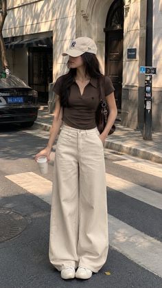 Woman in a brown polo shirt and wide leg pants on a city street