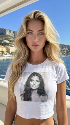 Blonde woman in a white cropped t-shirt on a boat with ocean and mountains in the background