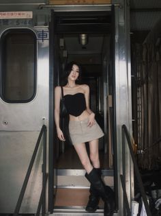 Woman in a black strapless top and mini skirt posing in a train car doorway
