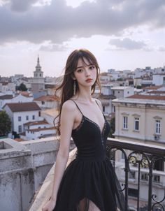 Woman in a black dress on a rooftop overlooking a cityscape under a cloudy sky