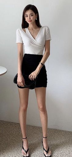 Woman in a white top and black mini skirt holding a small black bag