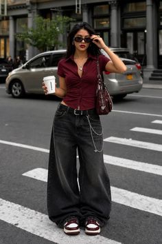 Woman in a maroon crop top and baggy jeans holding a Starbucks cup on a street