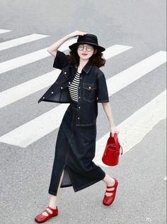Woman in a denim jacket and midi skirt walking on a crosswalk
