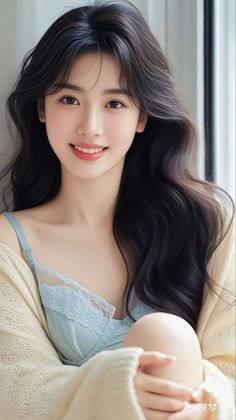 Woman with long black hair wearing a light blue lace bra and knitted cardigan