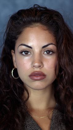 Woman with curly dark hair and hoop earrings in a close-up portrait