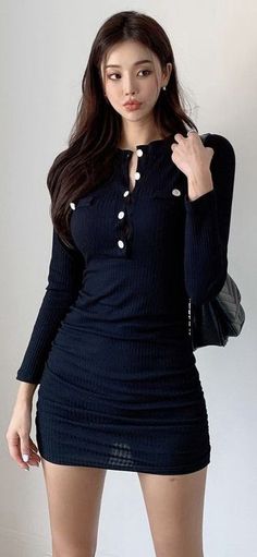 Woman in a tight black mini dress with long sleeves and white buttons