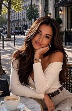 Woman with long brown hair at an outdoor cafe in a city