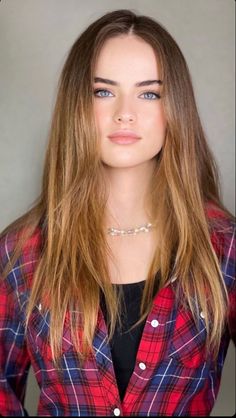 Woman with long hair and blue eyes wearing a red and blue plaid shirt