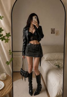 Woman in a black leather jacket and lace bralette taking a mirror selfie
