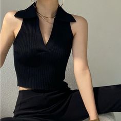 Person wearing a black collared sleeveless top with gold jewelry