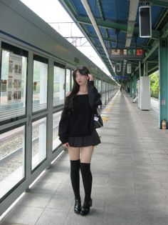 Woman with long dark hair wearing an off-shoulder top and mini skirt at a subway station